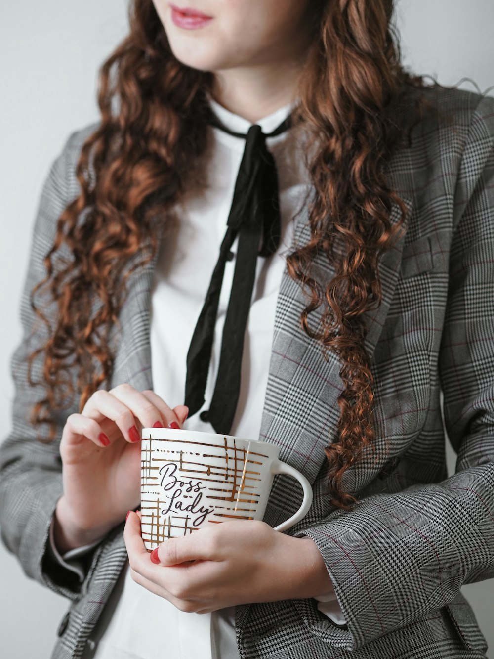 woman in gray blazer holding white and black ceramic mug