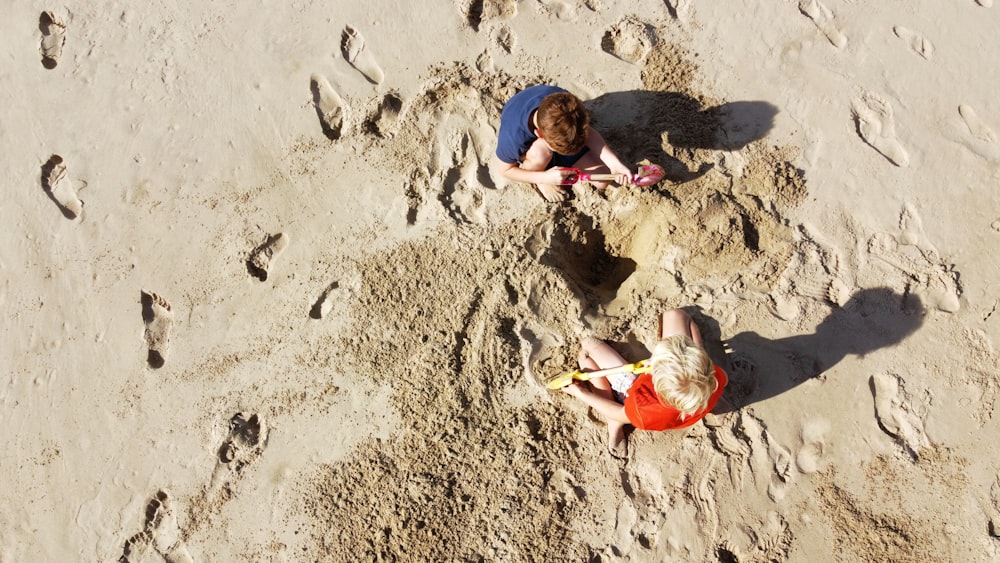 2 boys lying on sand during daytime