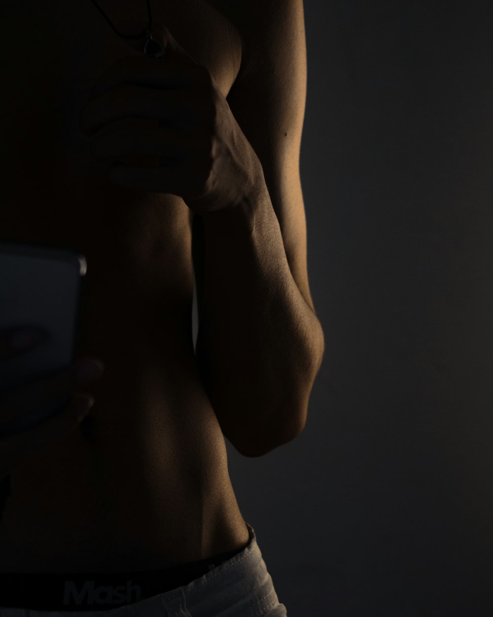 topless man holding white smartphone
