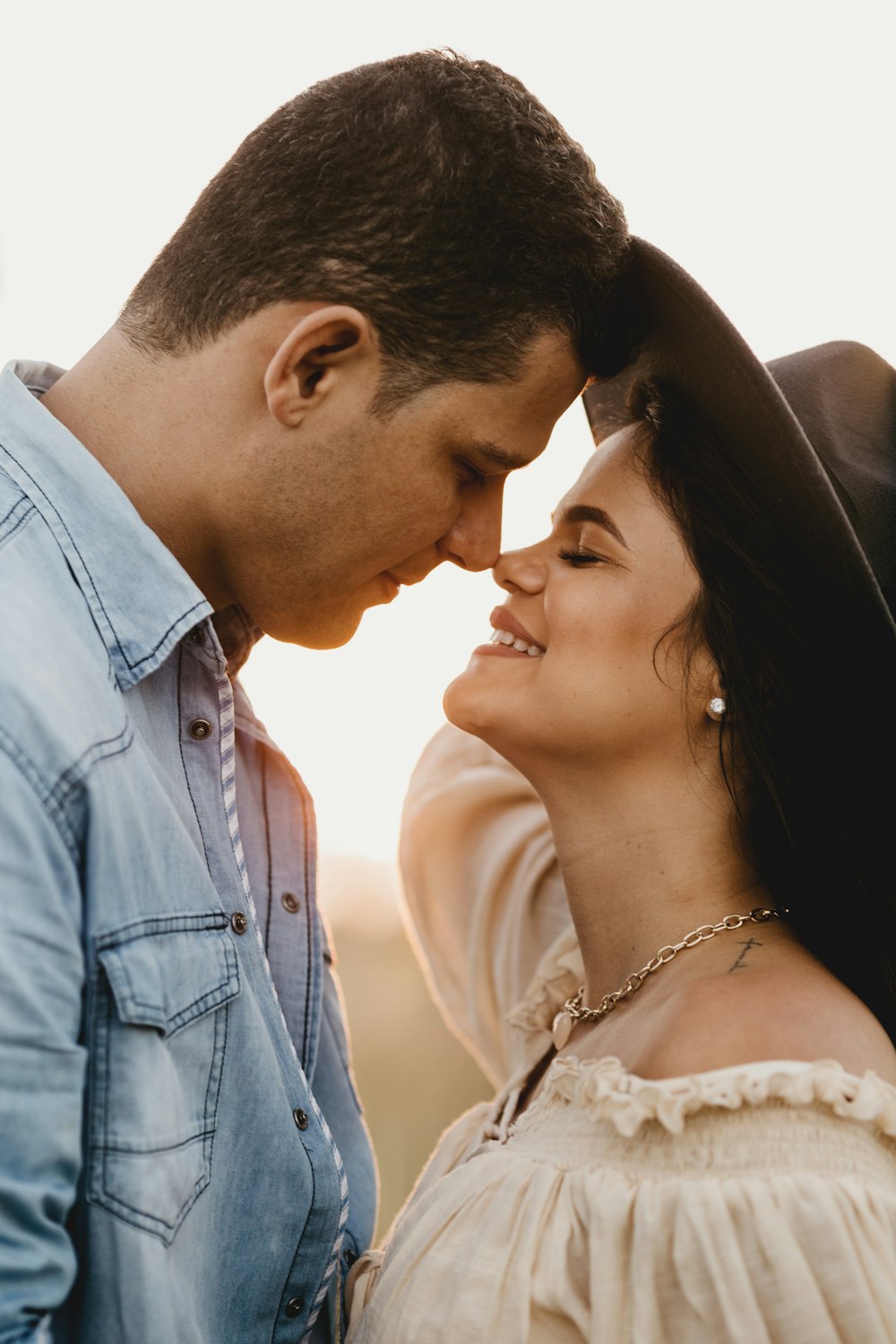 man in blue denim button up shirt kissing woman in white floral dress