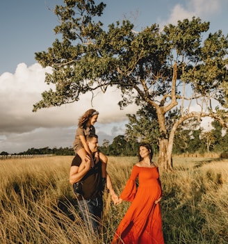 woman in orange dress standing beside green tree during daytime