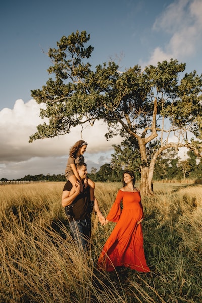 woman in orange dress standing beside green tree during daytime