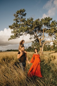 woman in orange dress standing beside green tree during daytime