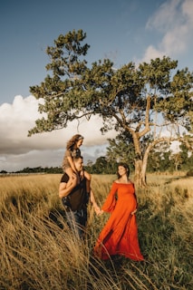 woman in orange dress standing beside green tree during daytime