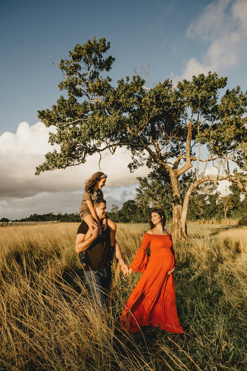 woman in orange dress standing beside green tree during daytime