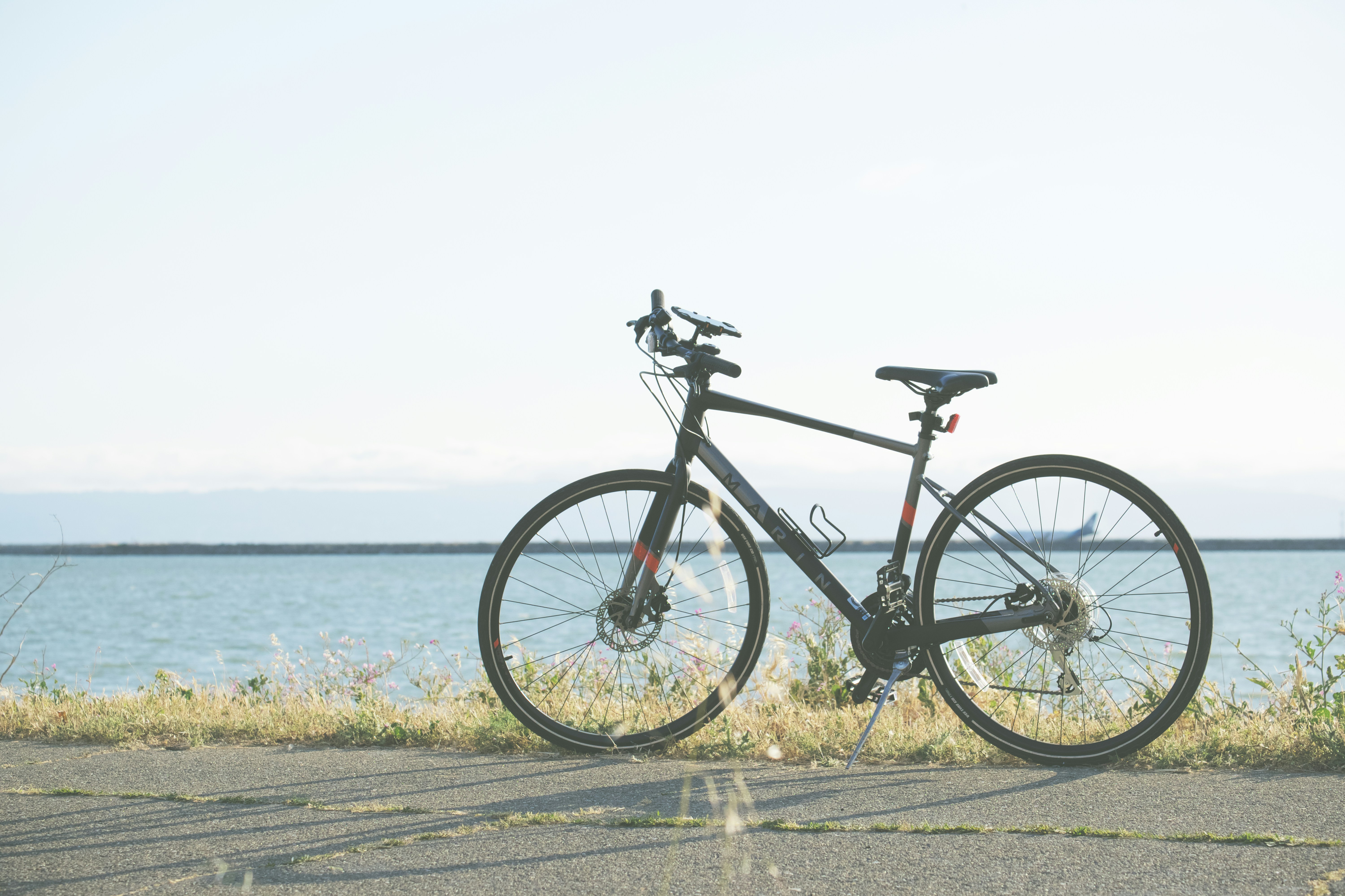 black and gray road bike on gray concrete road near body of water during daytime