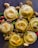 A collection of golden-brown ravioli is garnished with sliced mushrooms and various colorful peppers, all seasoned with black pepper and herbs on a dark surface. The arrangement is artful and appetizing, highlighting the textures and flavors of the dish.