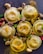 A collection of golden-brown ravioli is garnished with sliced mushrooms and various colorful peppers, all seasoned with black pepper and herbs on a dark surface. The arrangement is artful and appetizing, highlighting the textures and flavors of the dish.
