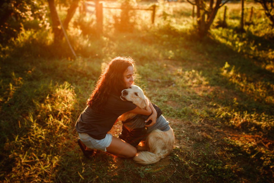woman in white long sleeve shirt and blue denim jeans sitting on ground with white dog