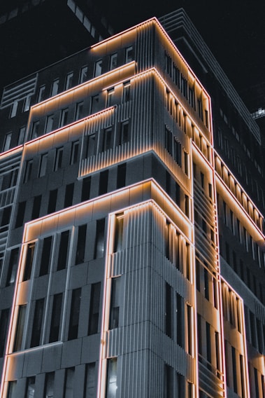 A modern building facade showcasing sleek construction and illuminated vintage lighting.