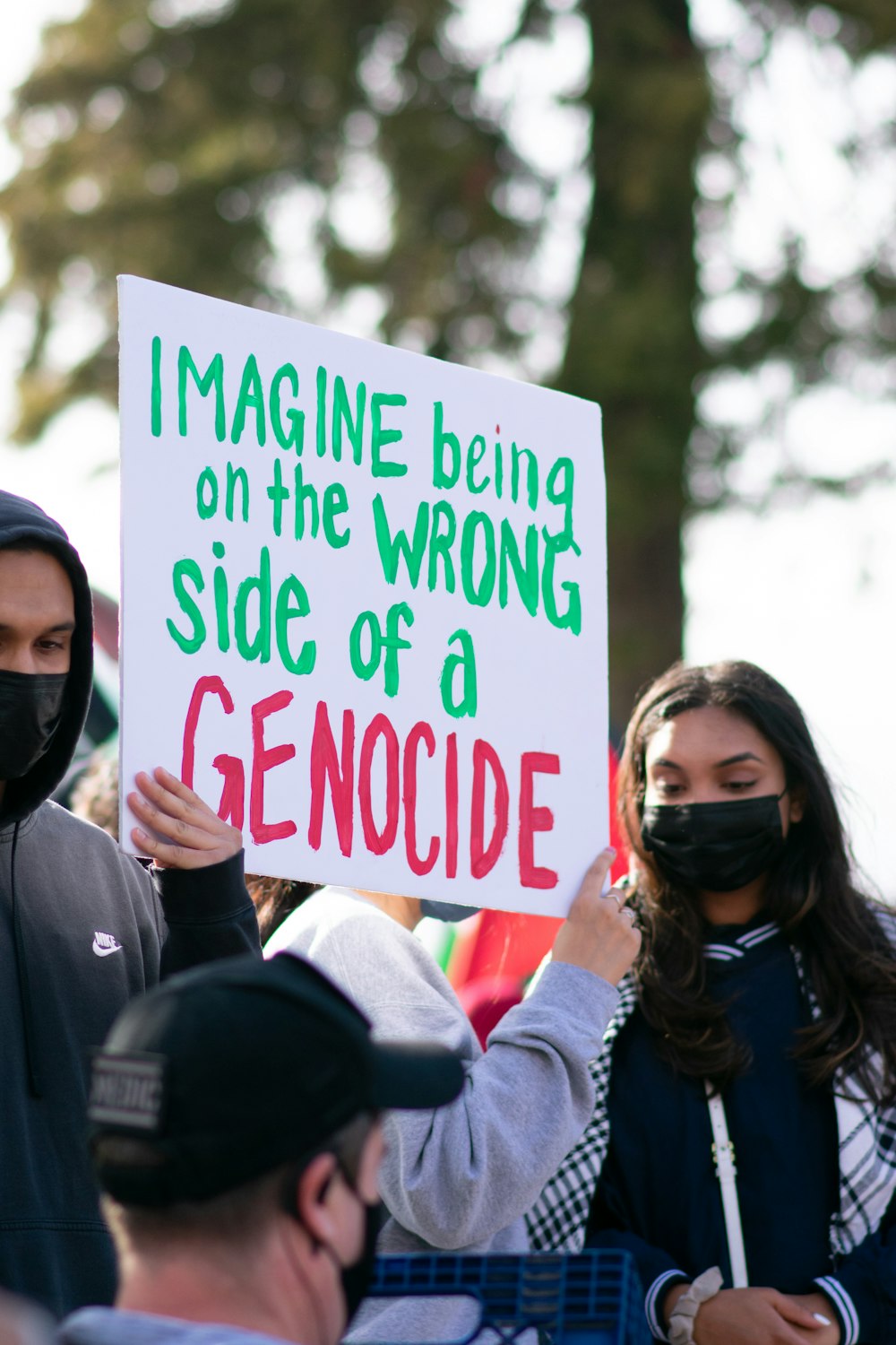 woman in black jacket holding white and red no smoking sign