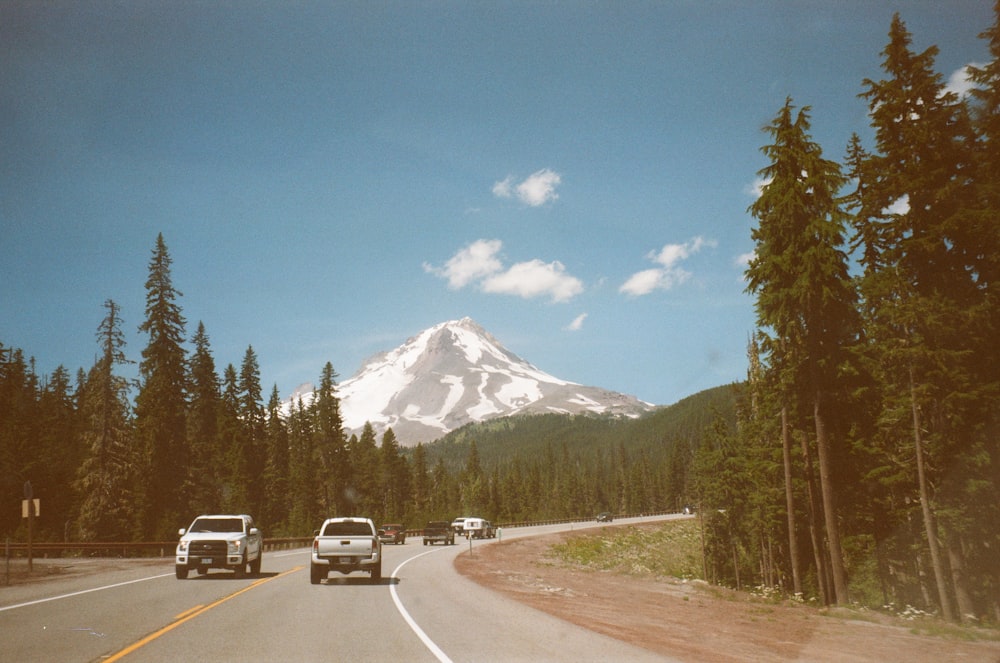 white car on road near green trees and mountain during daytime