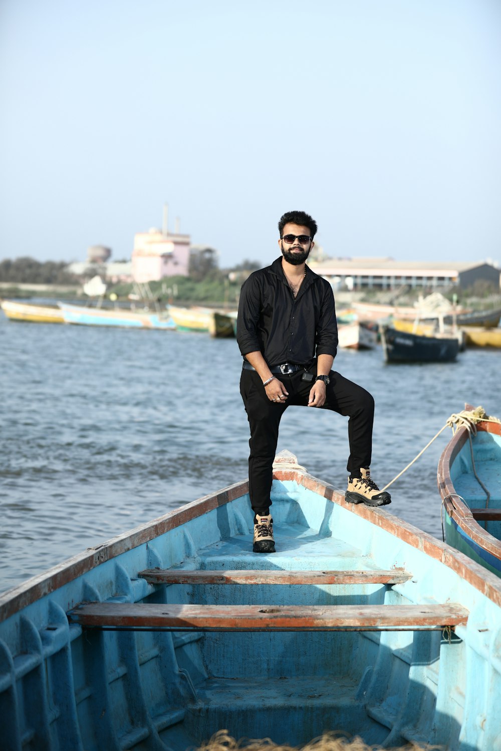 man in black t-shirt and black pants standing on brown wooden dock during daytime