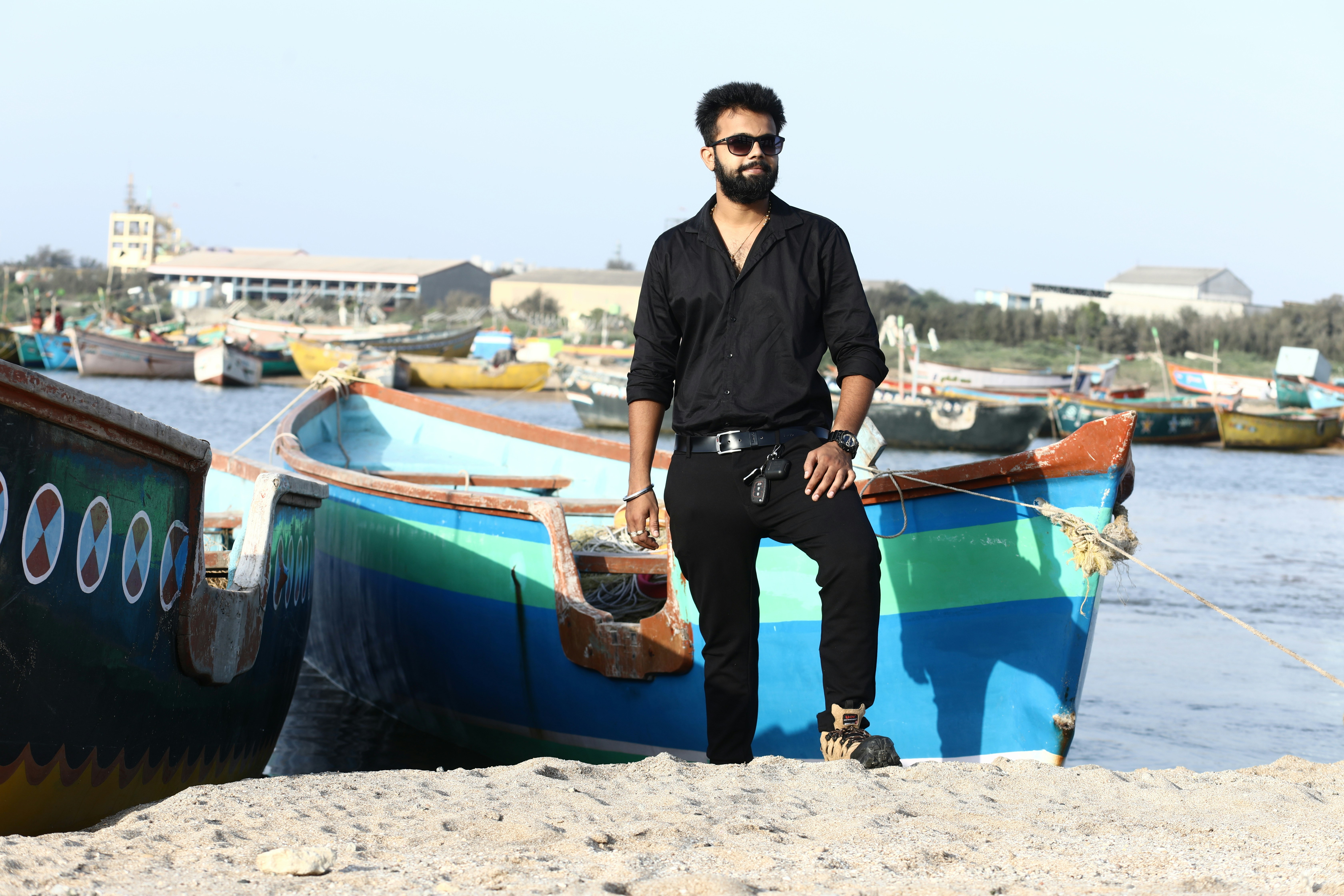 man in black polo shirt standing beside blue and white boat during daytime