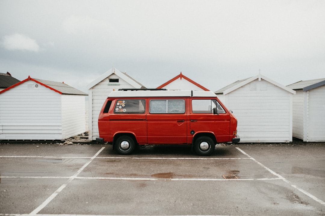 red van parked beside white and blue house