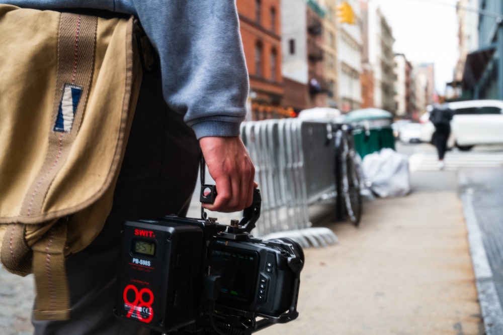 Person in blauen Jeans mit schwarzer DSLR-Kamera