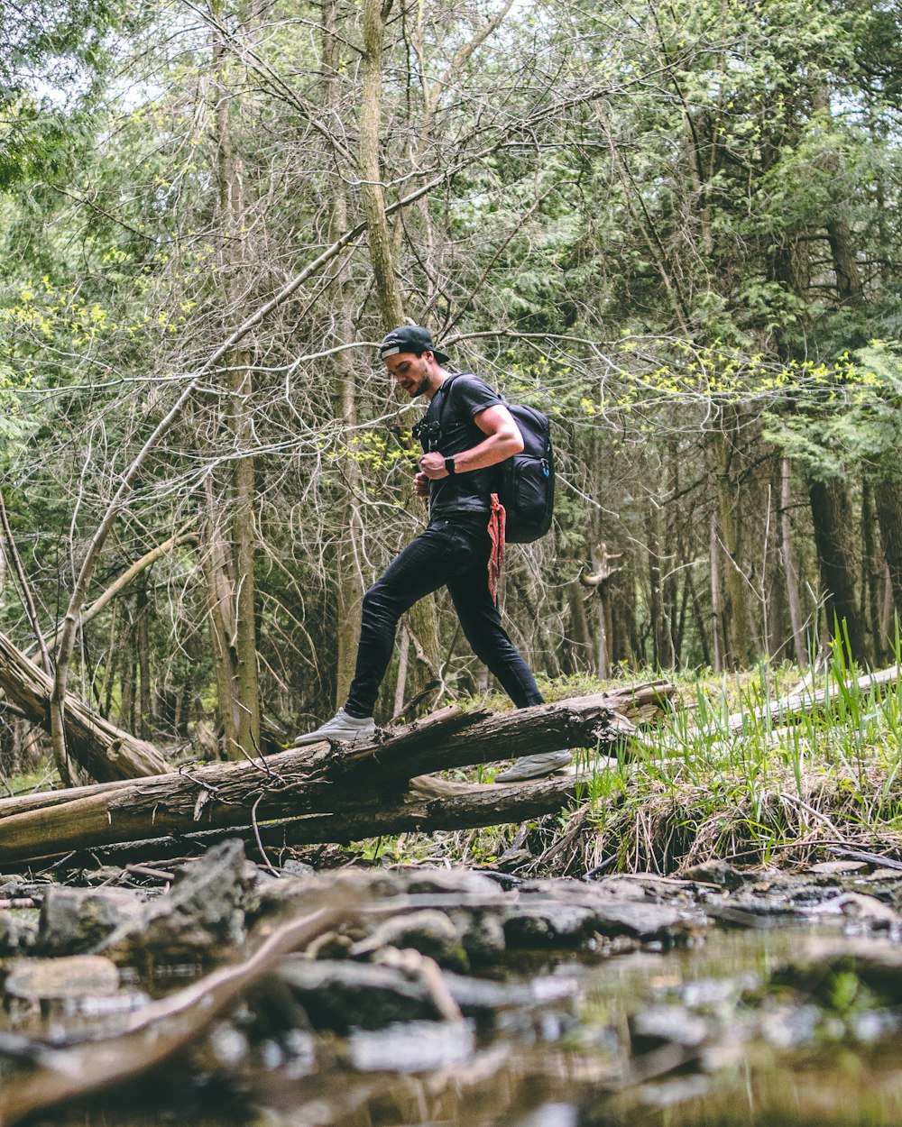 man in black jacket and black pants standing on tree log during daytime