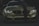 A stylish and aggressive-looking BMW car with its headlights on, displaying bold text 'FAKE TAXI' on the bumper. The car features a sleek, shiny surface with a dark green stripe running down the center of the hood and is set against a dimly lit background.