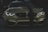 A stylish and aggressive-looking BMW car with its headlights on, displaying bold text 'FAKE TAXI' on the bumper. The car features a sleek, shiny surface with a dark green stripe running down the center of the hood and is set against a dimly lit background.