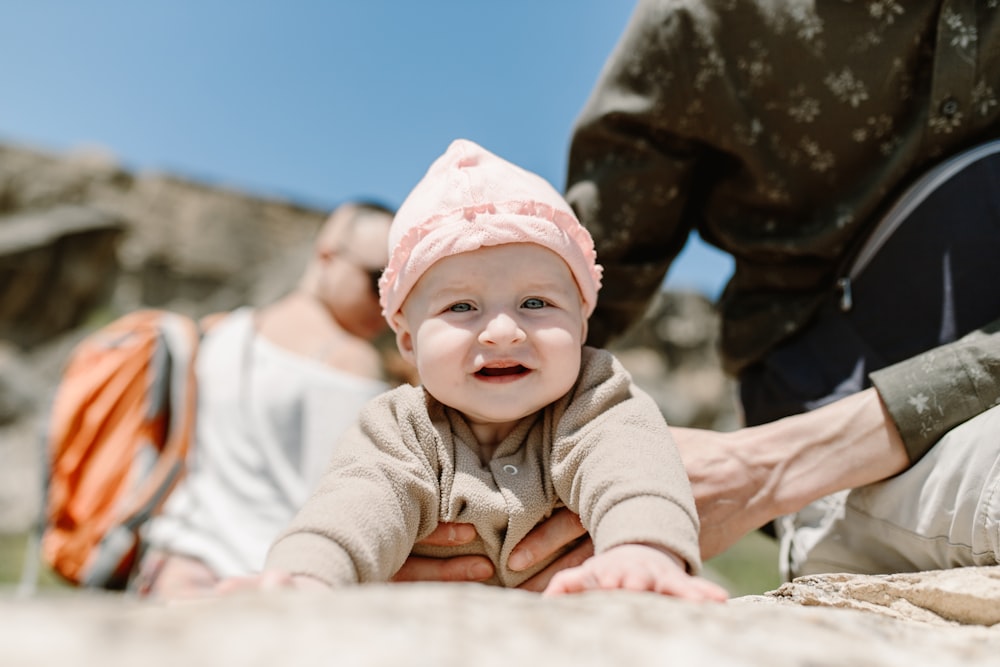 baby in gray and white jacket and pink knit cap