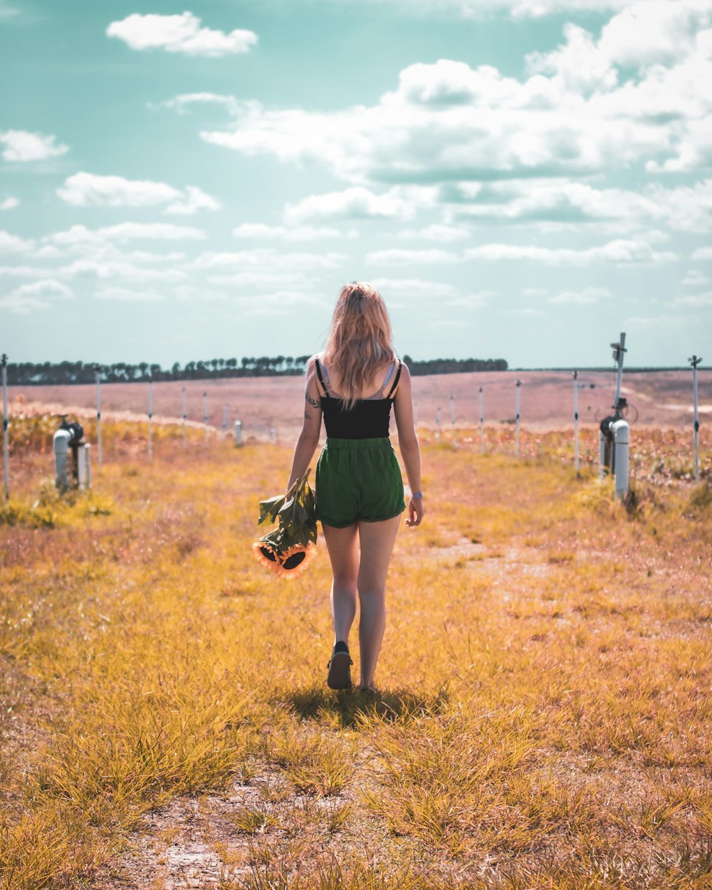 woman in green dress walking on brown grass field during daytime