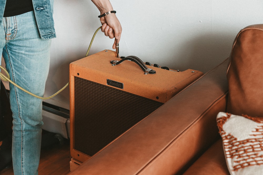 person holding brown guitar amplifier