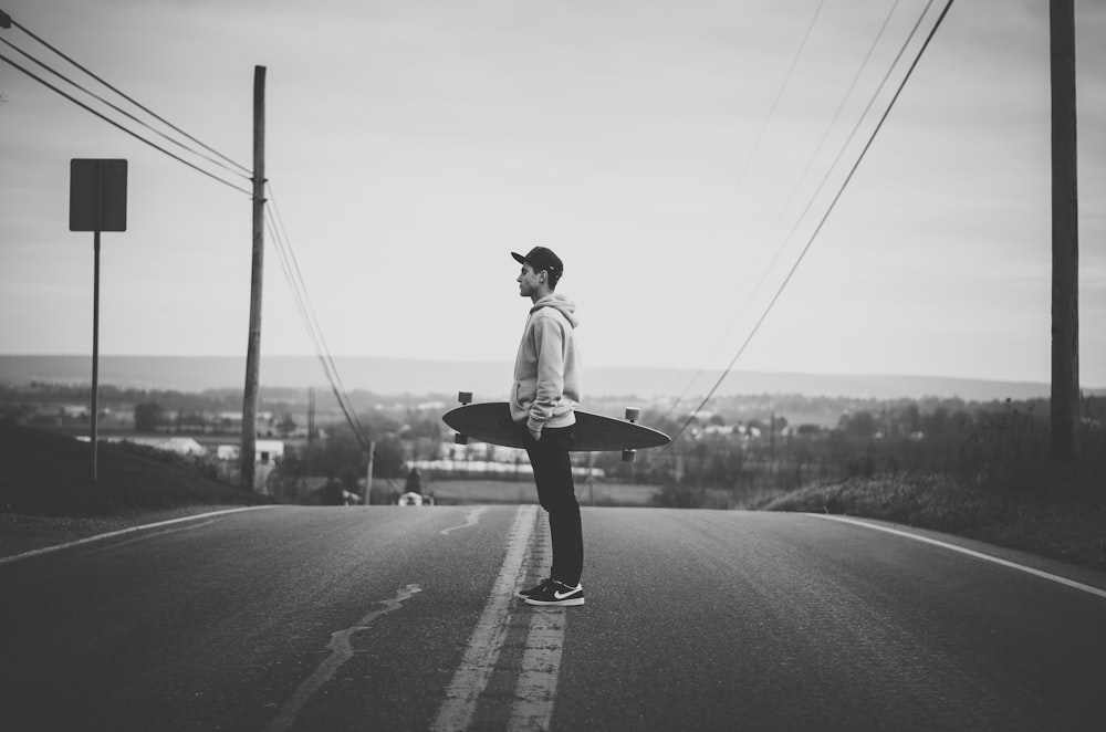 grayscale photo of man in white shirt and black pants walking on road