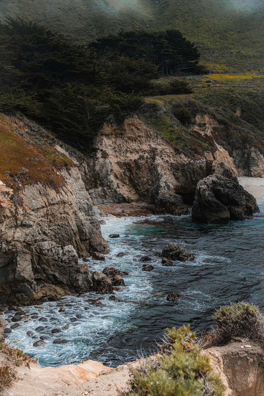 brown rocky mountain beside body of water during daytime