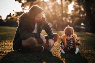 woman in black jacket sitting on ground beside girl in black jacket