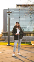 woman in gray coat and blue denim jeans sitting on bench during daytime