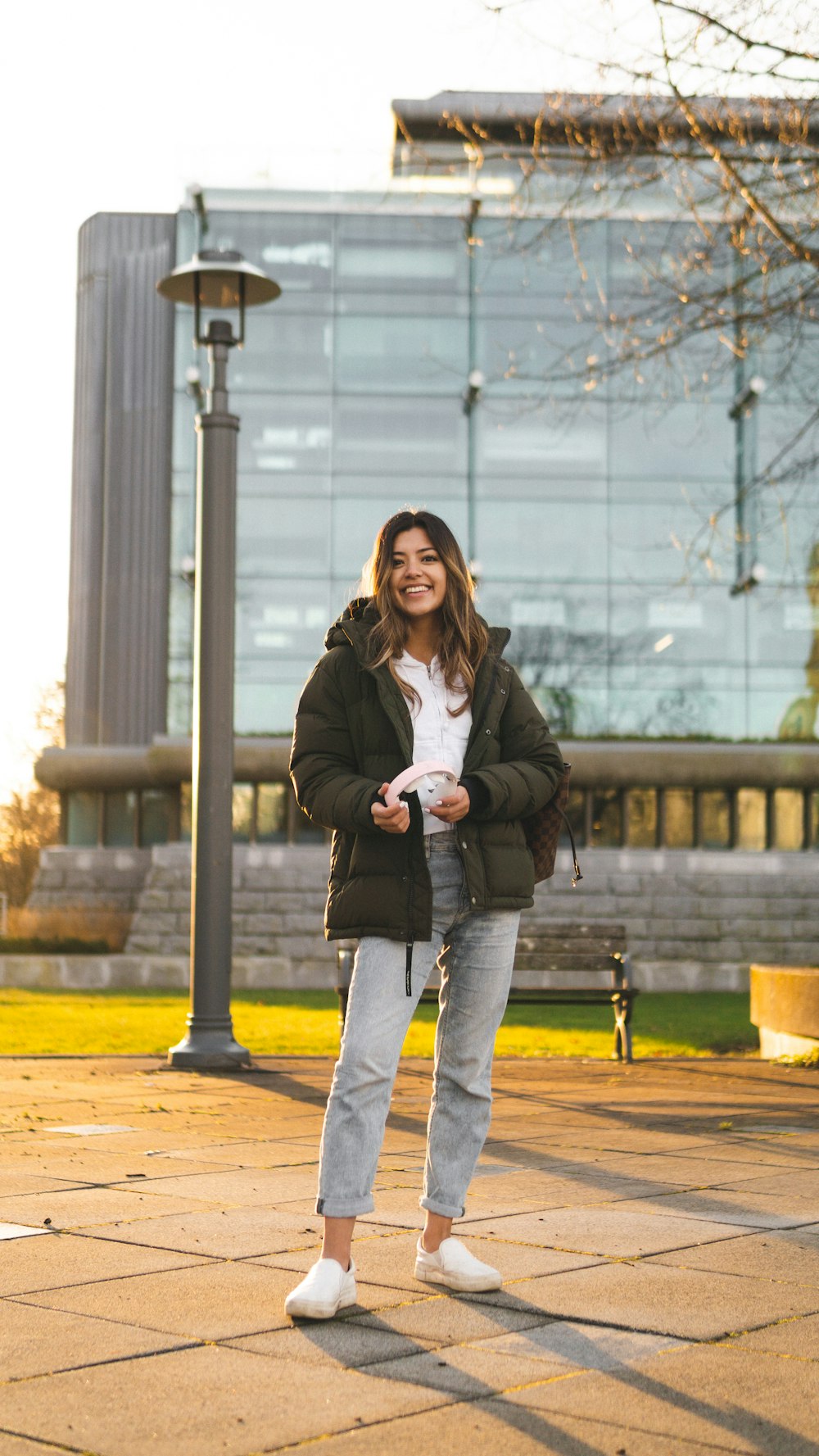 woman in gray coat and blue denim jeans sitting on bench during daytime