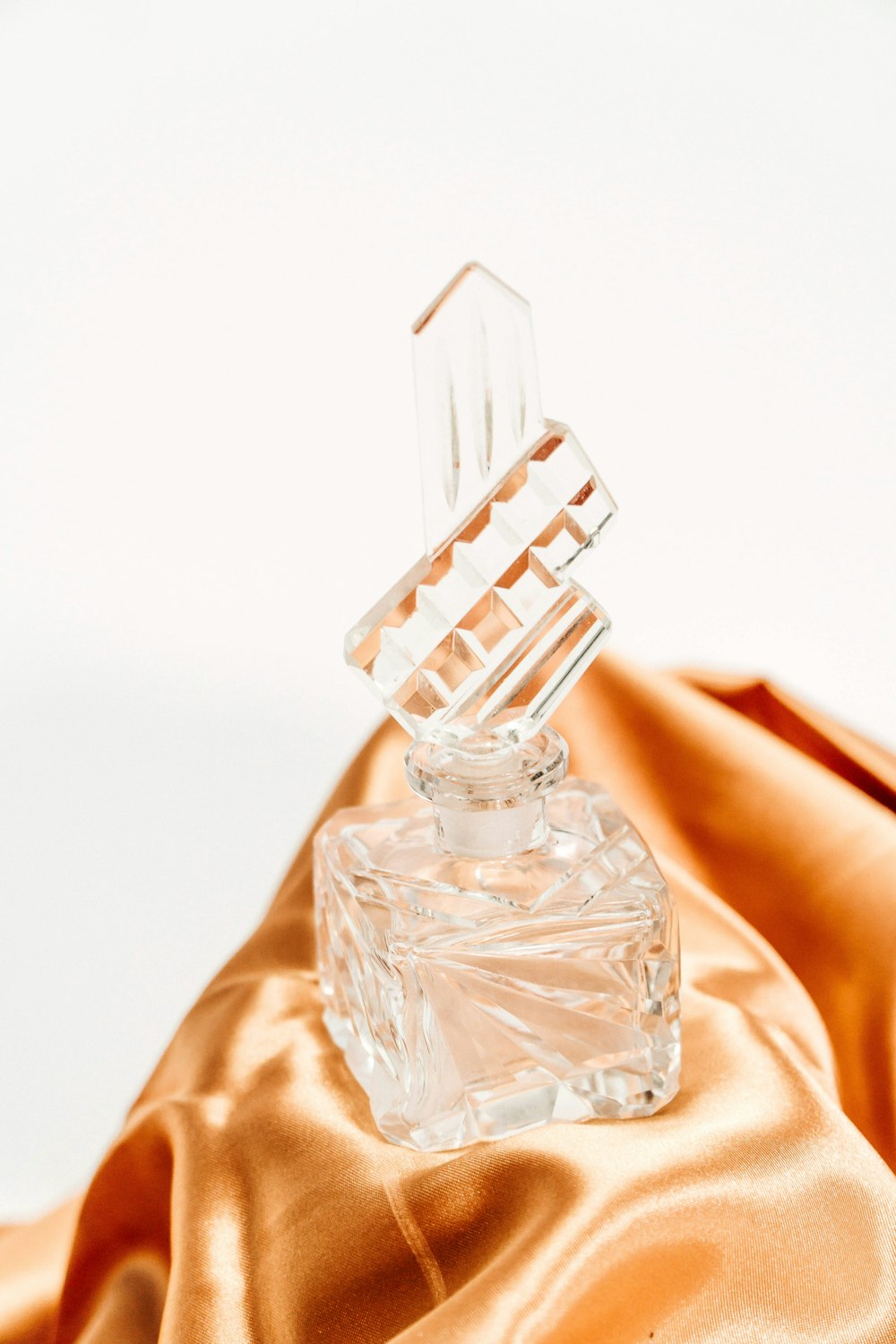 Frasco de perfume de vidrio transparente sobre textil marrón