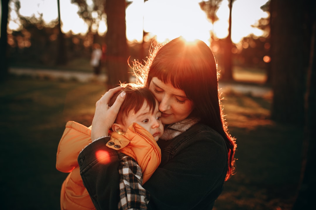 woman in black jacket carrying baby in red jacket