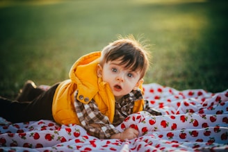 girl in orange hoodie lying on white and red blanket