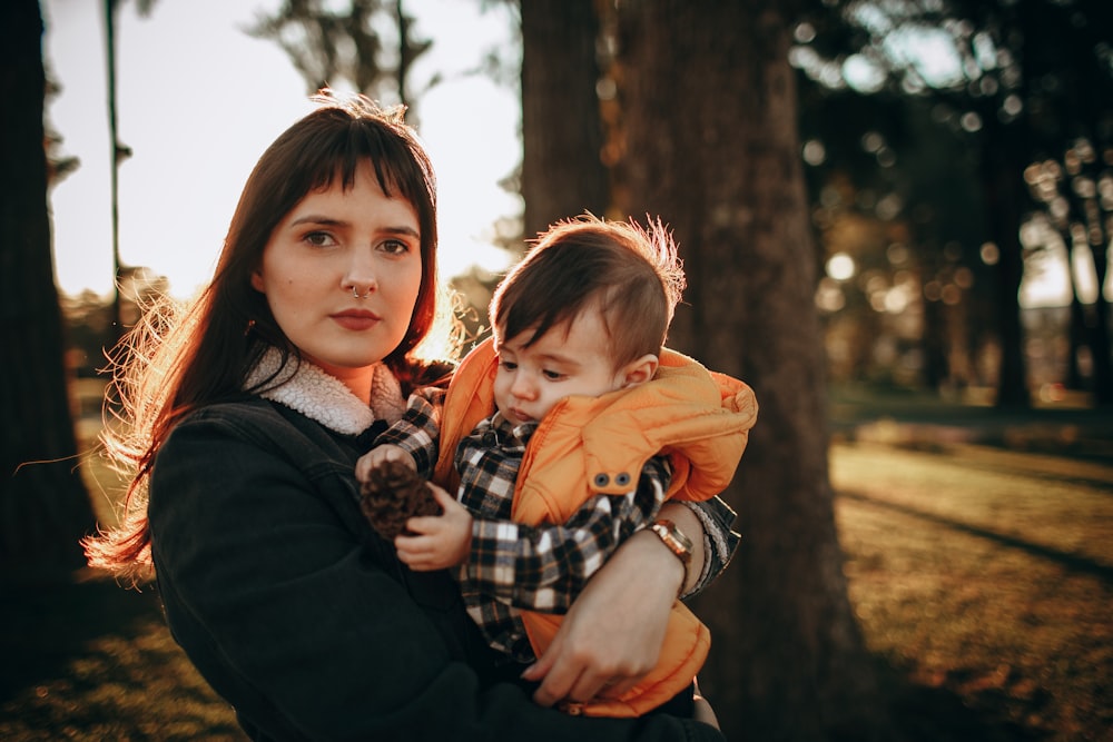 woman in black long sleeve shirt carrying girl in brown jacket