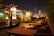 A cozy rooftop dining area with softly lit tables overlooking a city skyline at dusk.