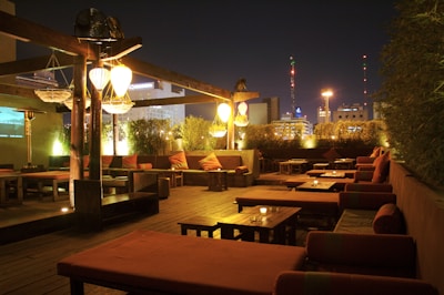 A cozy rooftop corner with warm lighting and comfortable seating at sunset.