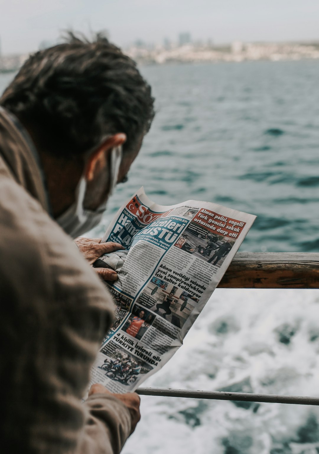 man in brown jacket holding newspaper