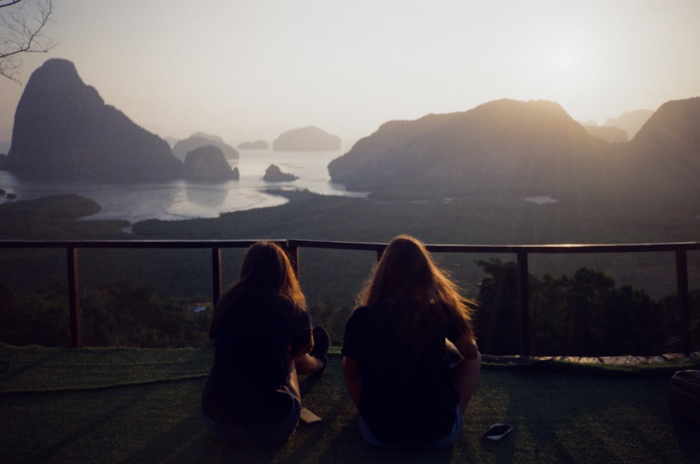 silhouette of 3 women sitting on ground during sunset