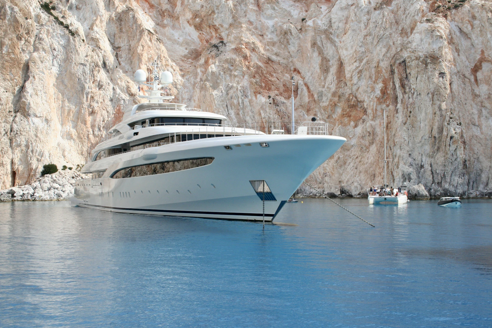 M/Y Aurelia — white tri-deck superyacht at anchor beneath pale limestone cliffs