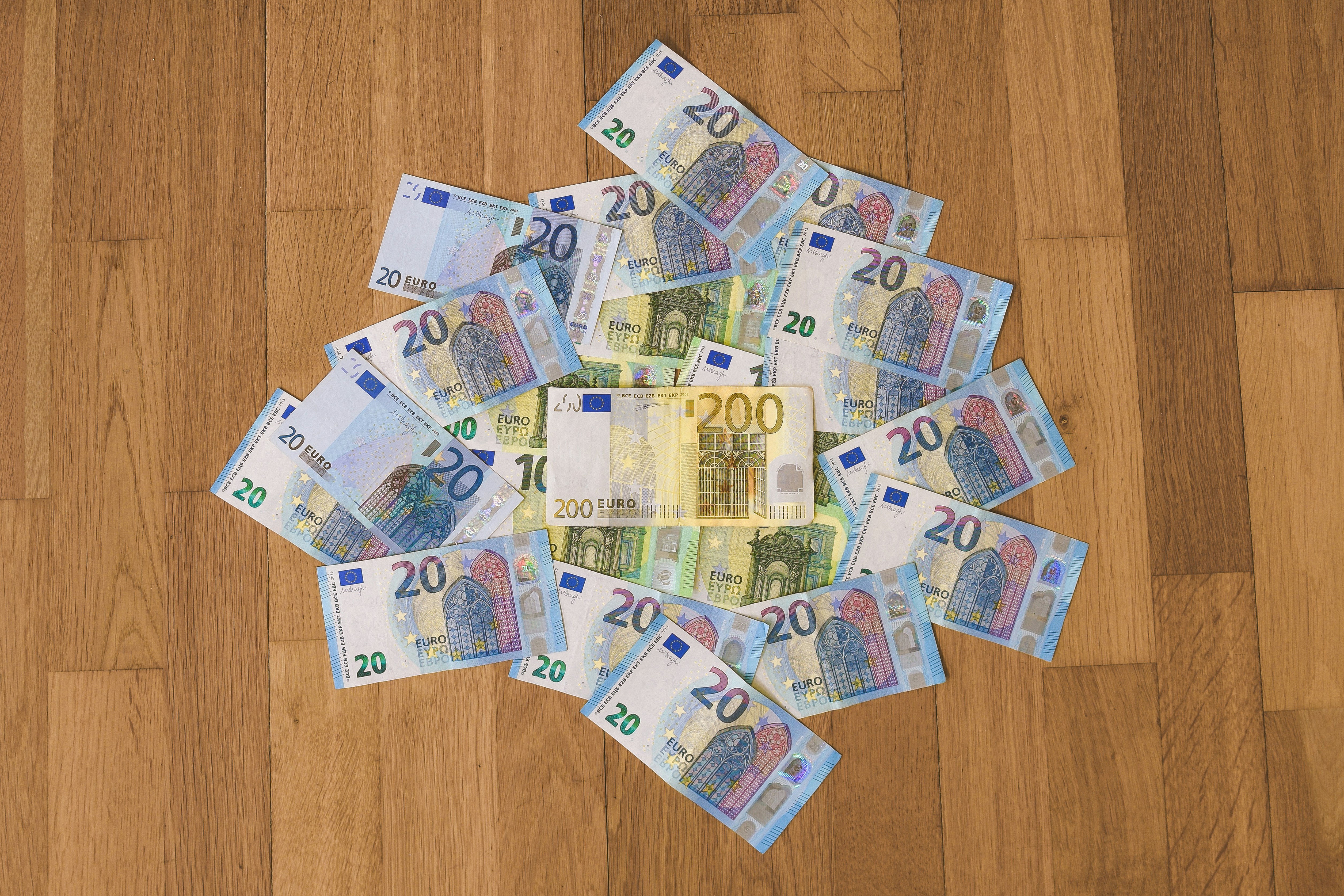 20, 100, and 200 Euro (EUR) banknotes placed on a wooden surface.