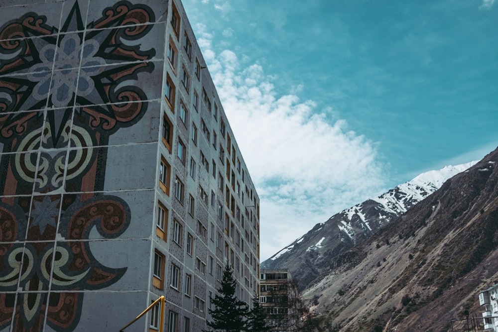 gray concrete building near trees and mountain under blue sky during daytime