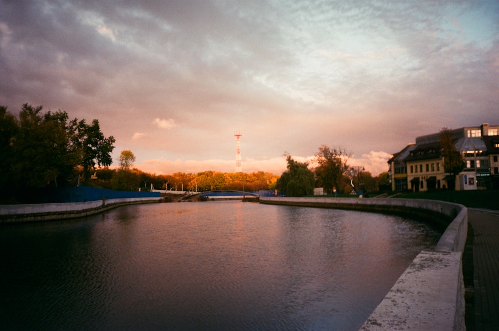 body of water near trees during sunset