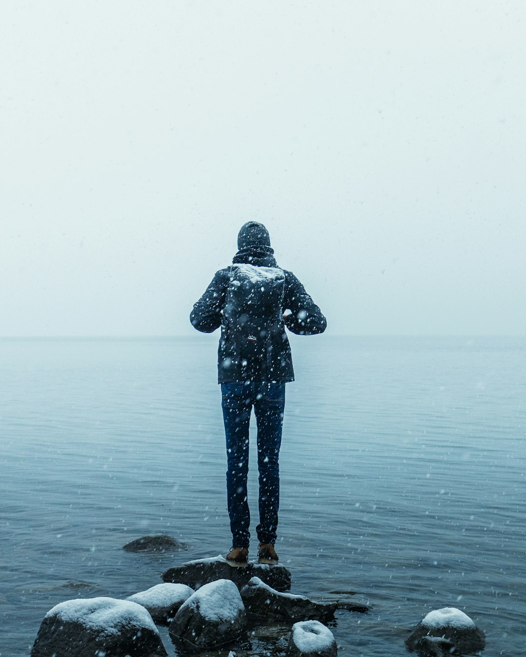 person in black jacket standing on sea shore during daytime