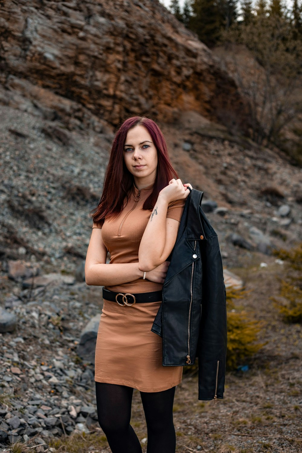 woman in black leather jacket standing near brown rock formation during daytime