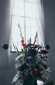 Bright and colorful artificial flower bouquet displayed near a window with natural light