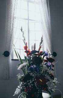 A beautifully arranged floral bouquet in vibrant colors placed on a windowsill.