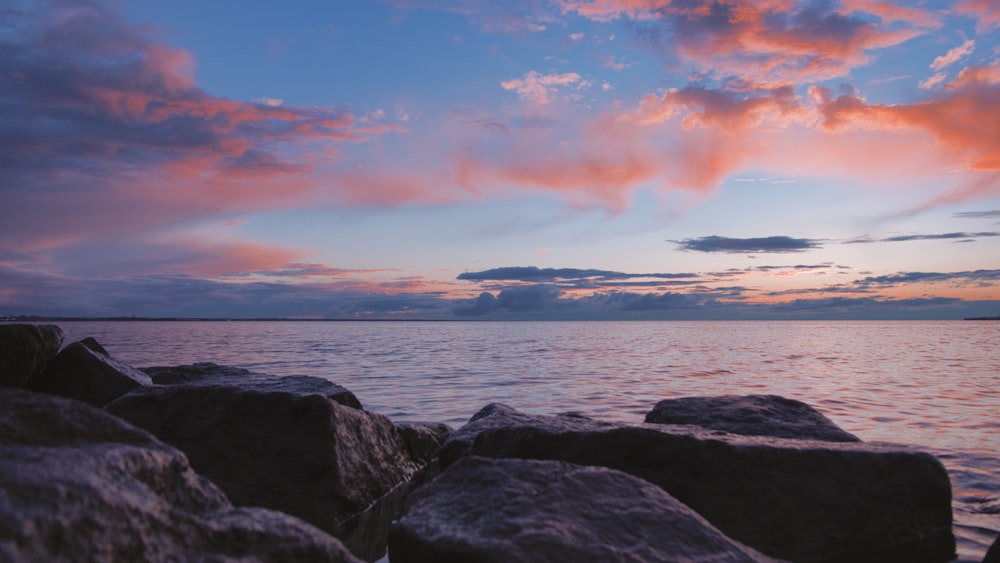 black and brown rocky shore during sunset