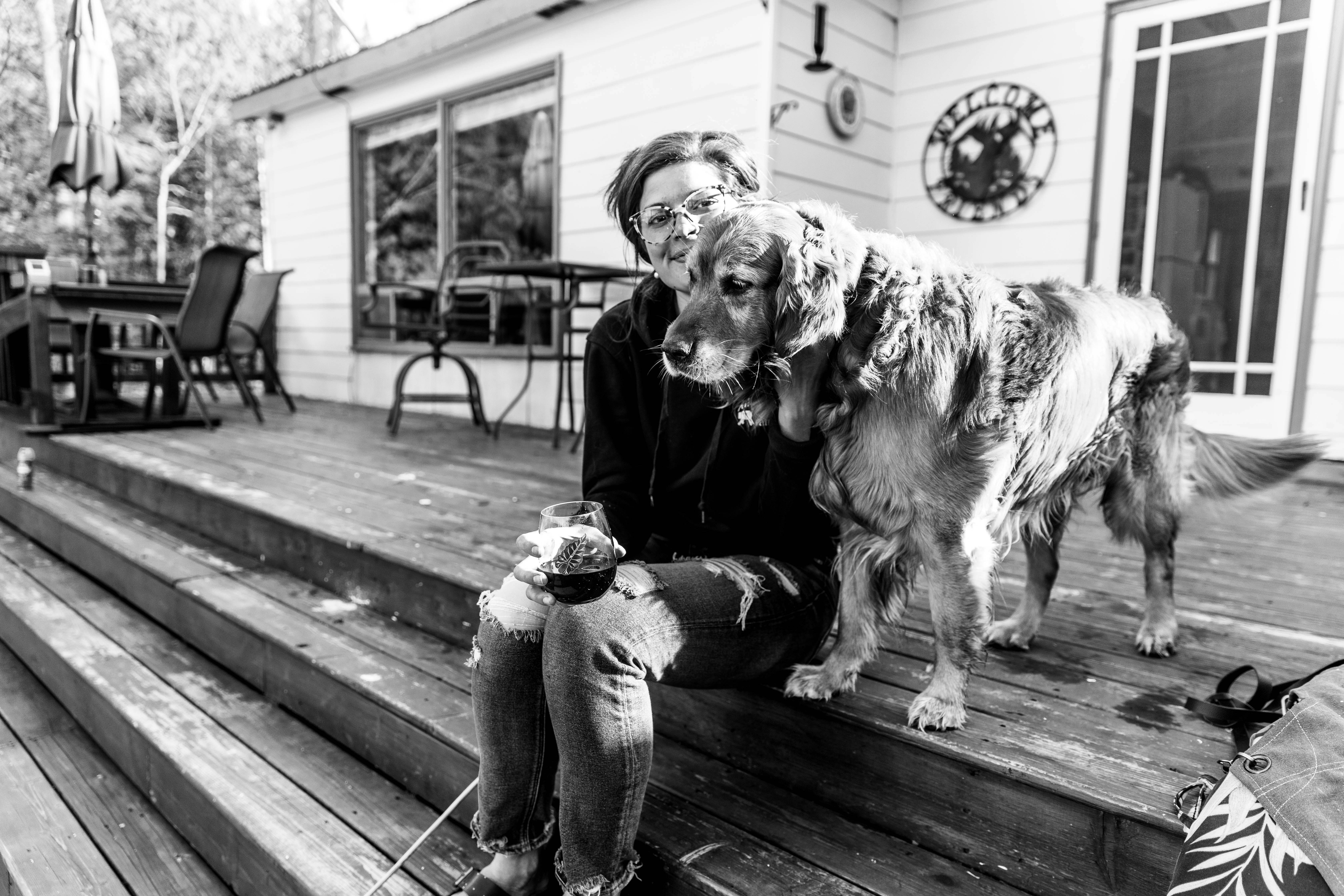 grayscale photo of woman and dog sitting on wooden floor