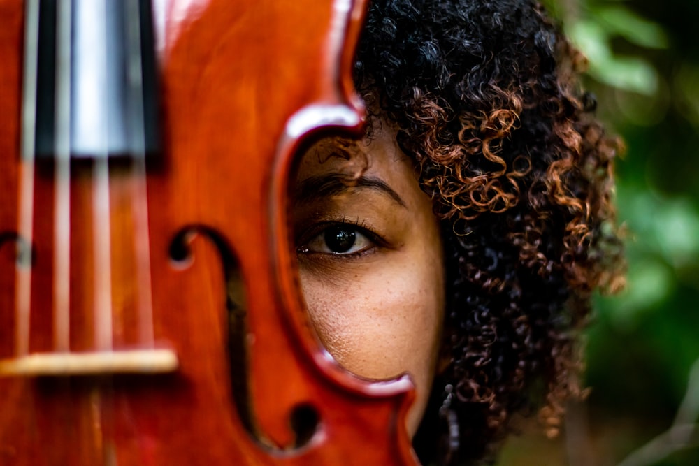 巻き毛と茶色の木製バイオリンを持つ女性